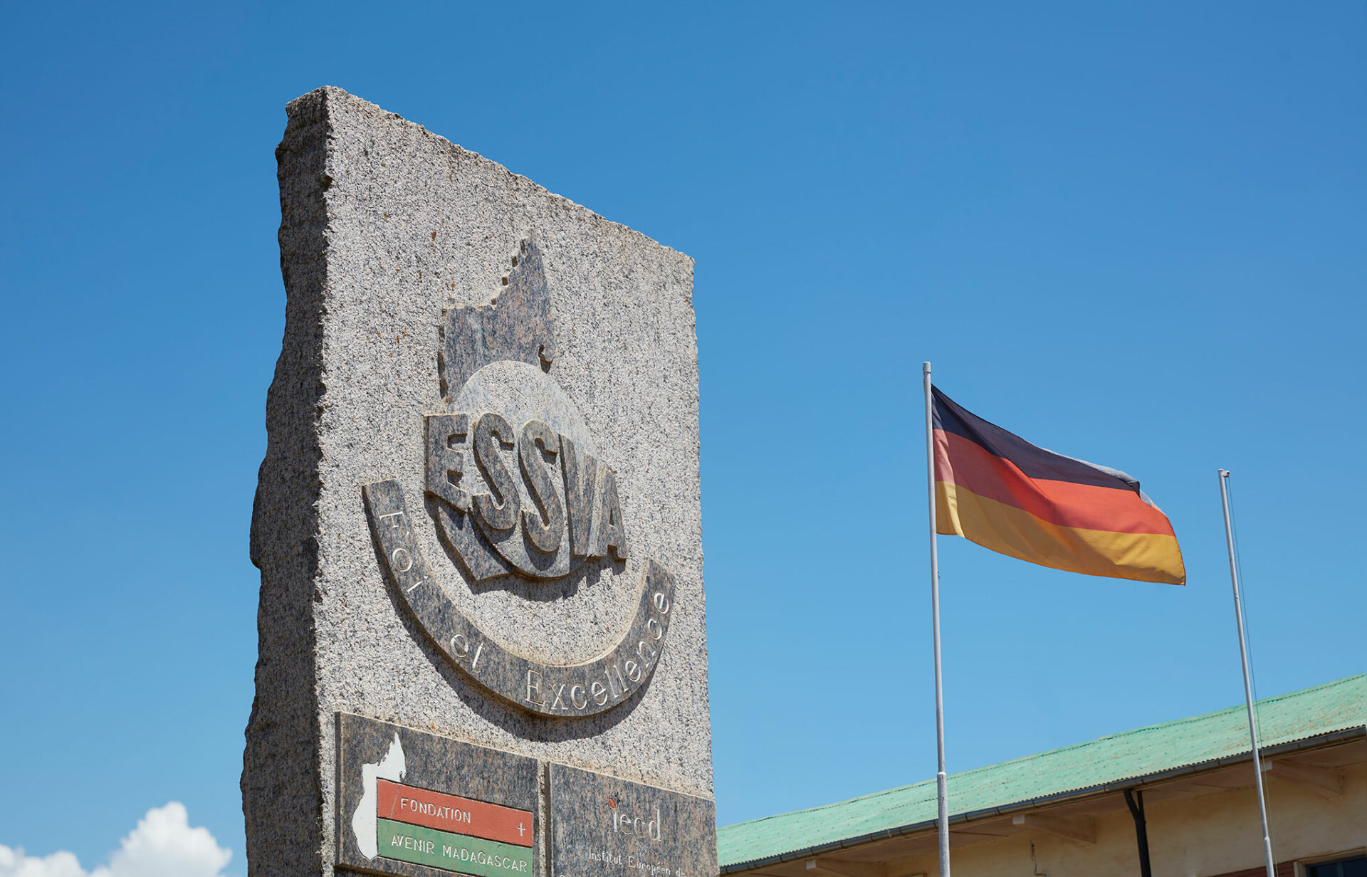 Denkmal der Hochschule ESSVA. Daneben ist eine Deutschland-Flagge zu sehen, um die Kooperation zu repräsentieren