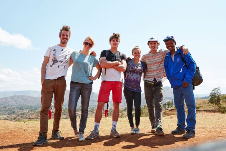5 junge Volontäre lächeln gemeinsam mit einem Einheimischen in die Kamera