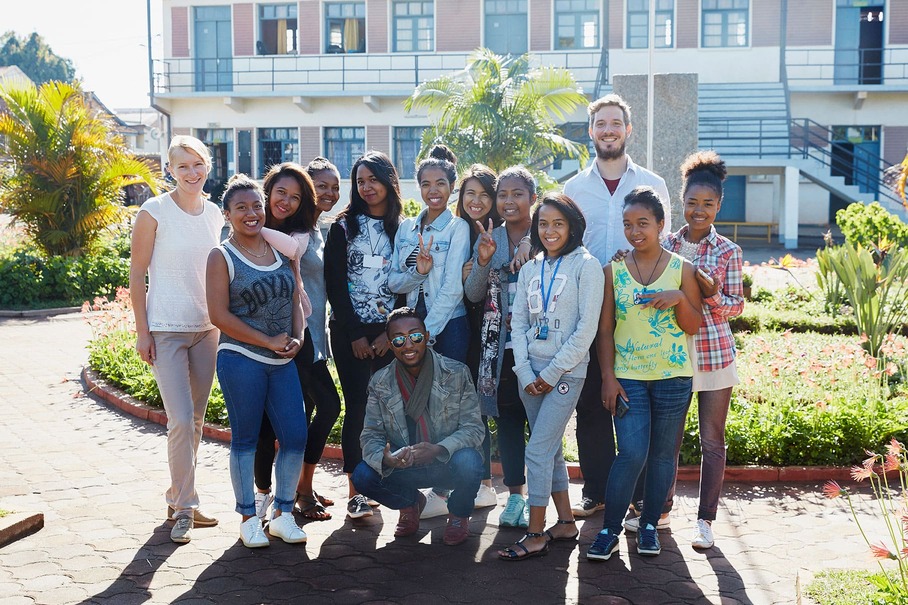 Ein Gruppenfoto der Volontäre mit madagassischen Schülerinnen und einem Schüler vor der Hochschule